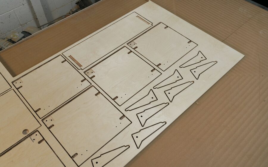 Laser-cut plywood parts laid out flat, still in their cut sheet