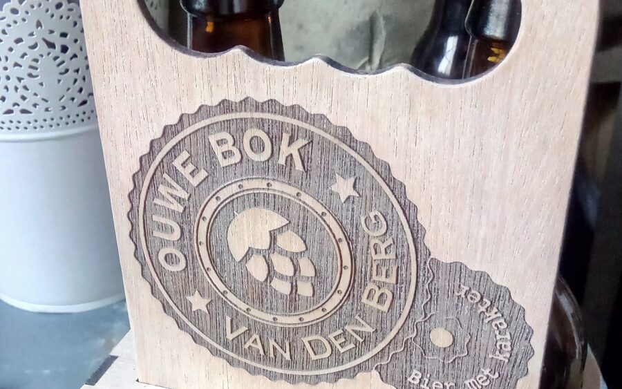 A brewery's round logo engraved into the plywood front panel of a bottle carrier