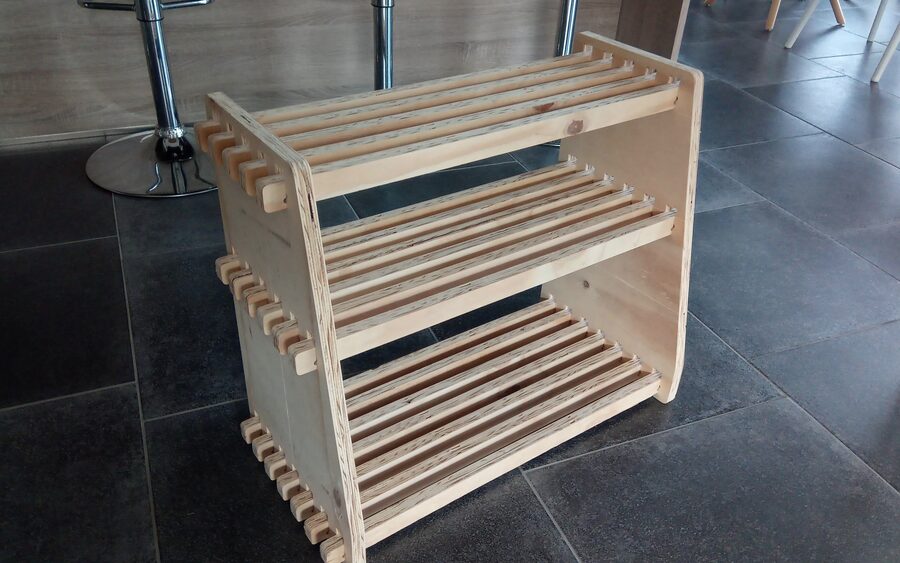 A three-tier plywood shoe rack with slatted shelves let into combed side panels